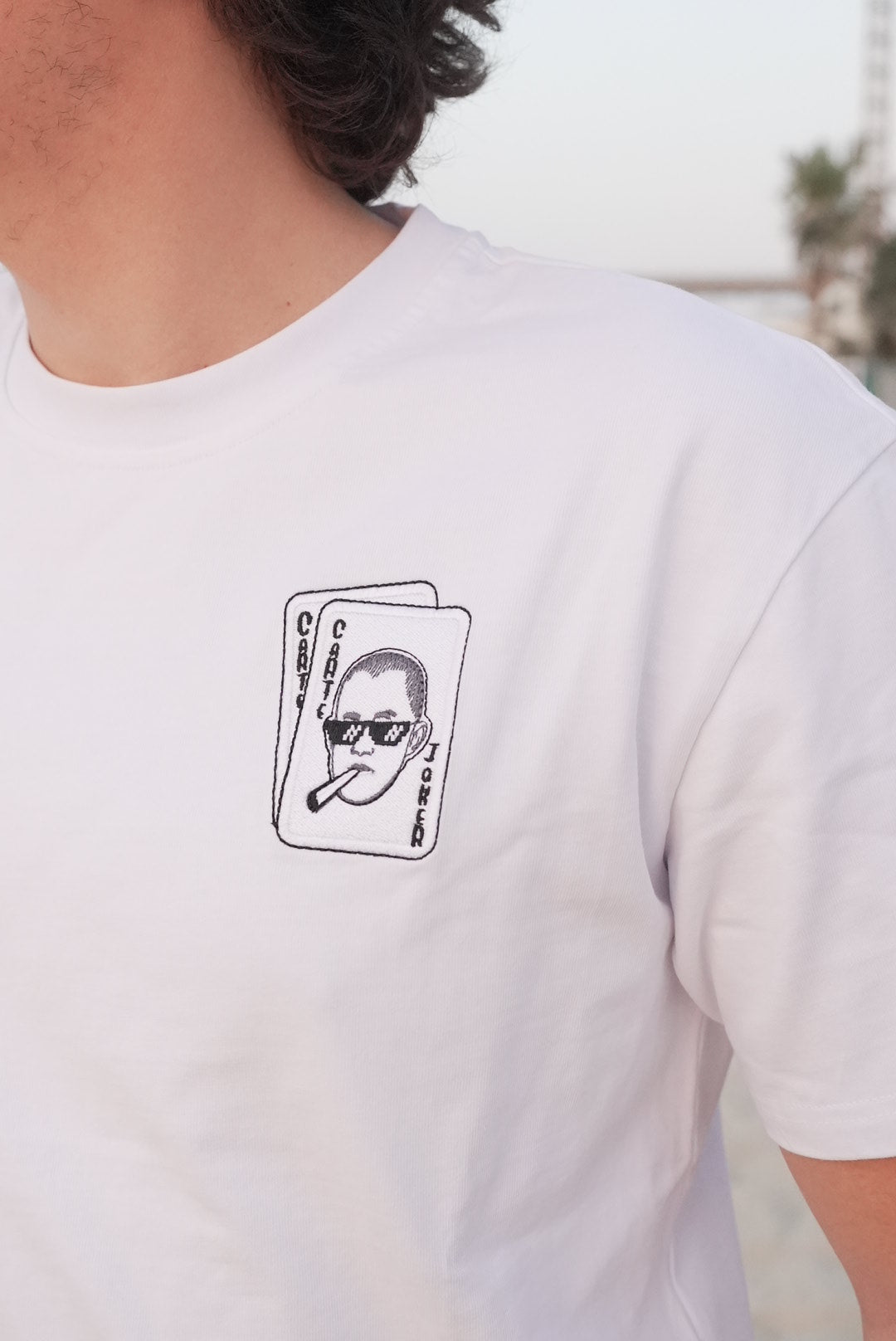 White t-shirt with a logo on the chest against a blurred background